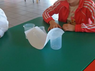 Zdjęcie przedstawia dziecko z PWD w Laskach uczestniczące w  zajęciach fizyczno-chemicznych z elementami matematyki podczas przygotowywania eksperymentu.