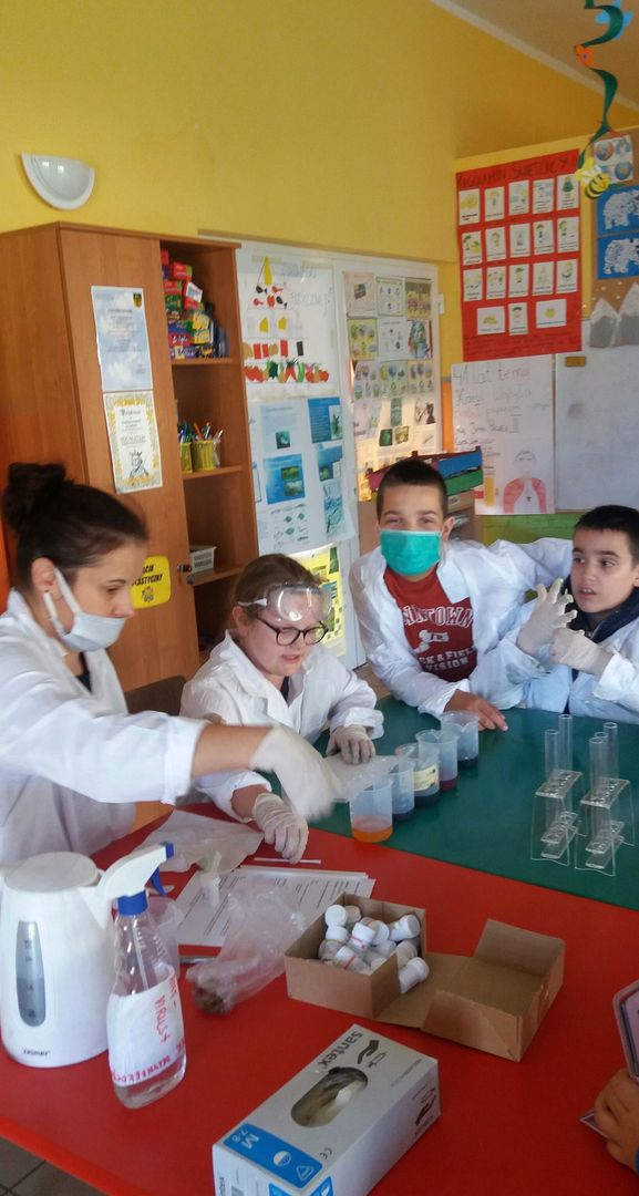 Zdjęcie przedstawia dzieci z PWD w Laskach uczestniczących w zajęciach fizyczno-chemicznych z elementami matematyki podczas przygotowywania doświadczenia.
