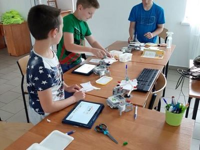 Zdjęcie przedstawia wychowanków PWD Przystawy podczas zajęć z robotyki ze składanymi przez nich robotami.