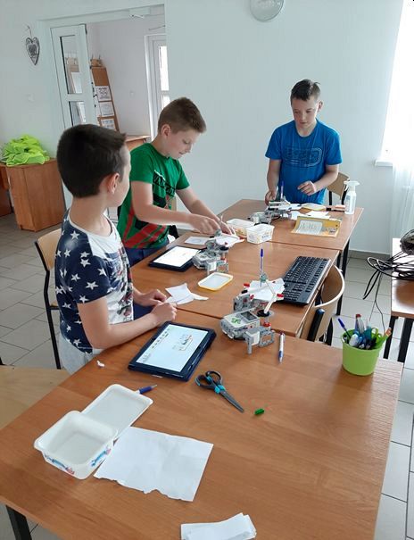 Zdjęcie przedstawia wychowanków PWD Przystawy podczas zajęć z robotyki ze składanymi przez nich robotami. 