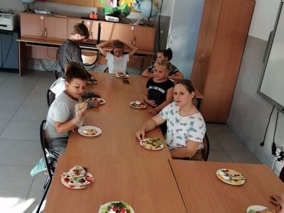 Zdjęcie przedstawia dzieci przy stole omawiające przygotowywanie kanapek w PWD w Kusicach.