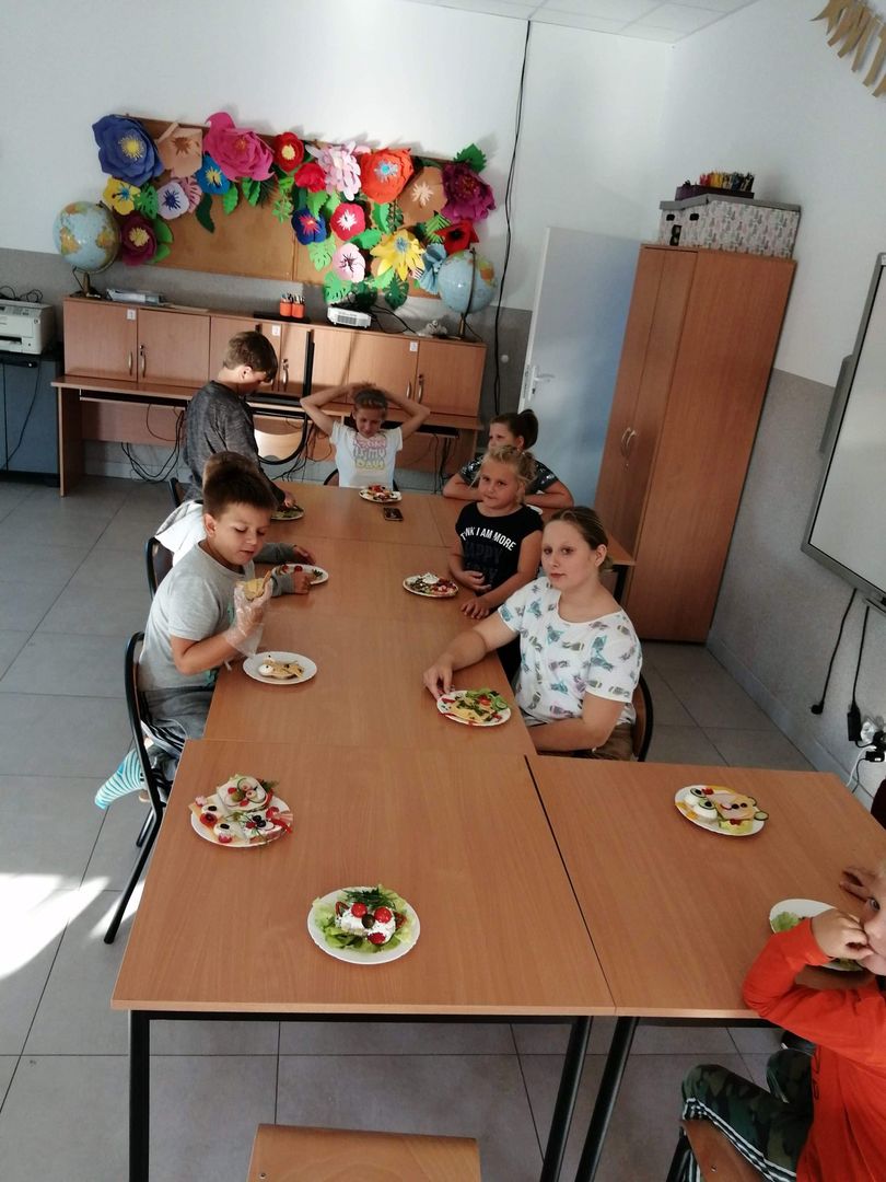 Zdjęcie przedstawia dzieci przy stole omawiające przygotowywanie kanapek w PWD w Kusicach.