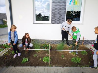 Zdjęcie przedstawia dzieci z PWD Kusice pracujące w przyświetlicowym ogródeczku.