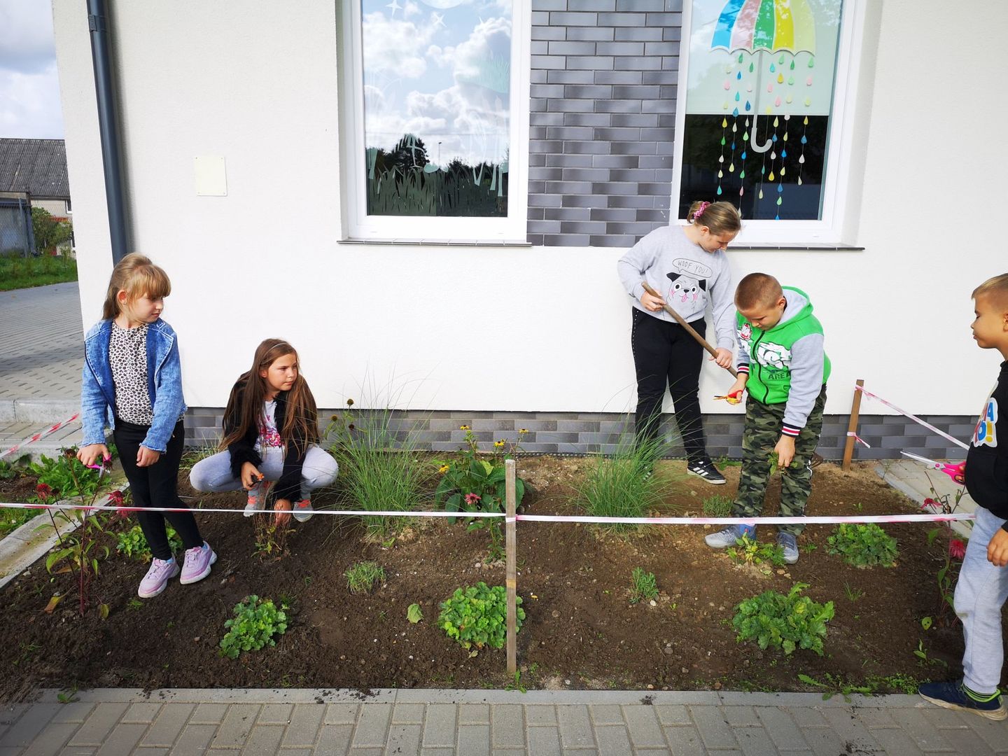 Zdjęcie przedstawia dzieci z PWD Kusice pracujące w przyświetlicowym ogródeczku.