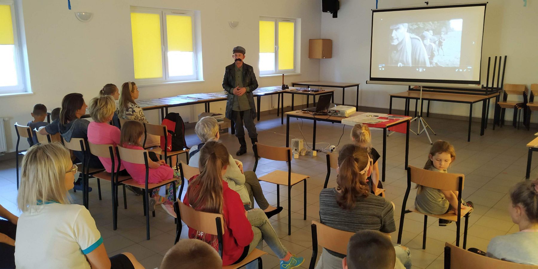 Na fotografii Pan Robert w stroju Marszałka Piłsudskiego oraz słuchające go dzieci, młodzież i dorośli.