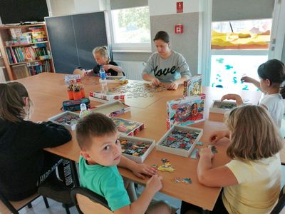 Zdjęcie przedstawia dzieci z Placówki Wsparcia Dziennego w Kusicach podczas konkursu polegającego na układaniu puzzli.