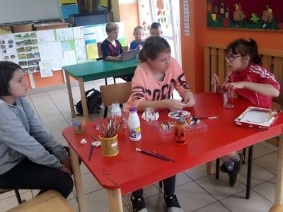 Zdjęcie przedstawia dzieci z PWD z Lasek, które malują na szkle farbami.