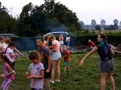 Dzieci z Karwic biorą udział w festiwalu kolorów i posypują się kolorowymi proszkami.