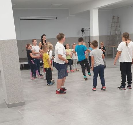 Zdjęcie przedstawia dzieci uczestniczące w zajęciach breakdance w Świetlicy Kultury w Malechowie wraz z instruktorką.