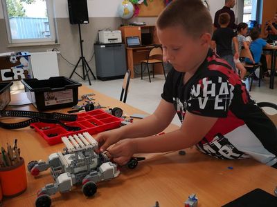 Zdjęcie przedstawia chłopca podczas konstrukcji robota podczas zajęć robotyki w PWD Kusice.