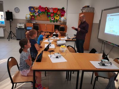 Zdjęcie przedstawia grupę dzieci wraz z prowadzącym, który wyjaśnia jak wykonać ćwiczenie w PWD Kusice.