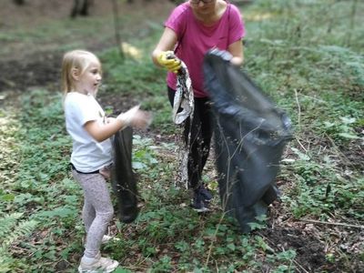 Zdjęcie przedstawia wychowawczynię PWD w Gorzycy pomagającą dzieciom w zbieraniu nieczystości.
