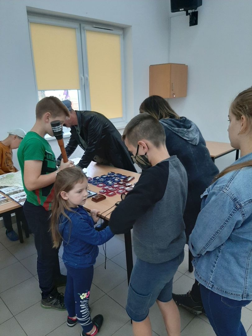 Zdjęcie przedstawia dzieci uczestniczące w lekcji bibliotecznej i podziwiające przedstawione zbiory.
