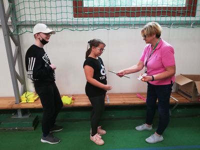 Zdjęcie przedstawia nauczycielkę wręczającą pamiątkowe nagrody uczestnikom akcji #BeActive w Lejkowie. 
