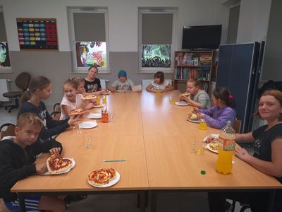 Zdjęcie przedstawia dzieci podczas jedzenia pizzerek.