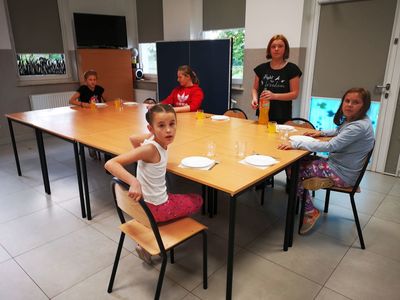 Grupę dzieci z PWD Kusice rozkładająca talerze na stół.