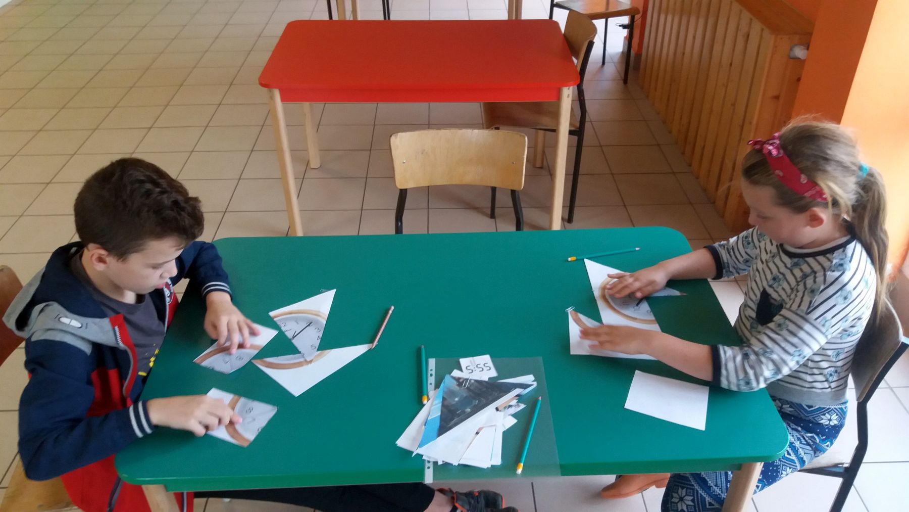 Wychowankowie PWD Laski układający zegary z elementów.