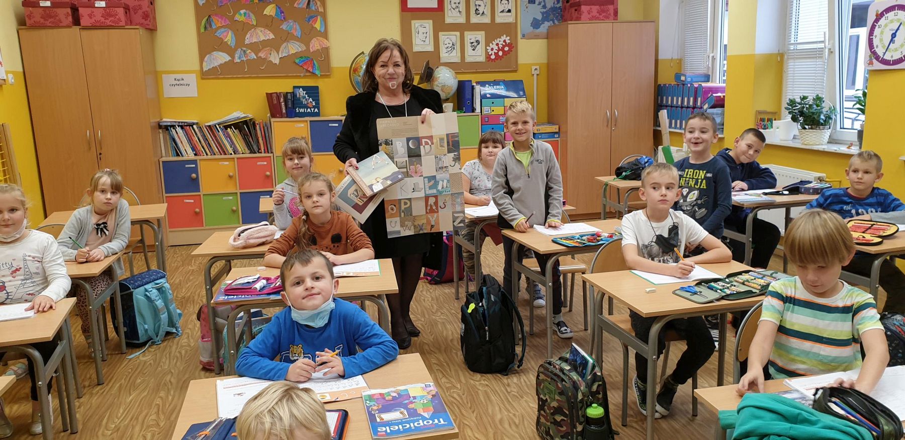 Dyrektor SP Niemica - Iwona Nowak-Gancarz prezentuje uczniom klasy I Wyprawkę Czytelniczą.