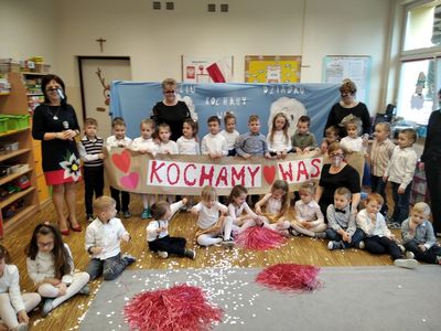 Przedszkolaki z Ostrowca z transparentem Kochamy Wam wraz z wychowawczyniami oraz dyrektor placówki. 