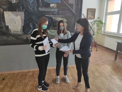 Dyrektor Zespołu Szkół w Ostrowcu wręcza stypendia uczennicom w budynku szkoły.