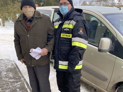 Strażak z OSP Malechowo pomaga seniorowi w przejściu do Punktu Szczepień. 