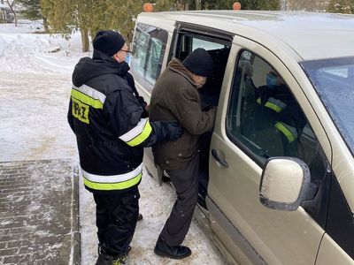 Strażak z OSP Malechowo pomaga seniorowi wsiąść do auta. 