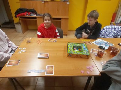 Dzieci z Placówki Wsparcia Dziennego z Podgórek w świetlicy po zimowej zabawie, grają w gry planszowe i rozgrzewają się przy herbatce. 