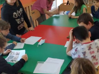 Wychowankowie z PWD Laski, którzy oglądają zdjęcia zwierząt.