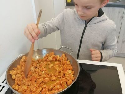 Uczestnik zajęć kulinarnych podczas smażenia mięsa.