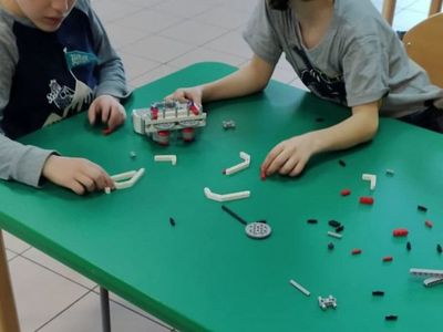Wychowankowie budując roboty z klocków lego.