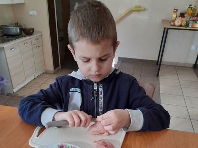 Chłopiec z Placówki Wsparcia Dziennego w Sulechowie kroi mięso drobiowe w ramach prowadzonych warsztatów kulinarnych.