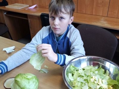 Chłopiec z Placówki Wsparcia Dziennego w Karwicach podczas przygotowywania surówki.