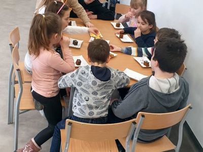 Grupa dzieci przy stole podczas zajadania się ciastem. 