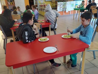 Wychowankowie Placówki Wsparcia Dziennego z Lasek podczas jedzenia sałatki w ramach zajęć kulinarnych.