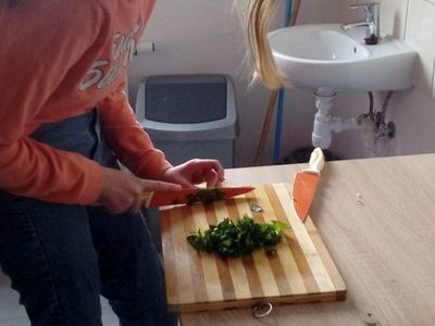 Dziewczynka z Placówki Wsparcia Dziennego z Ostrowca kroi natkę pietruszki.