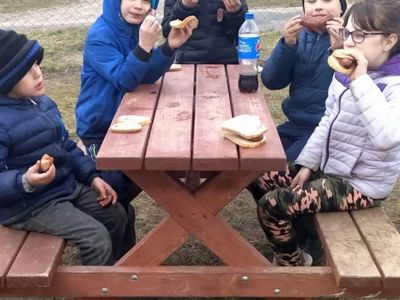 Dzieci z Placówki Wsparcia Dziennego w Laskach, jedzące kiełbaski z ogniska.
