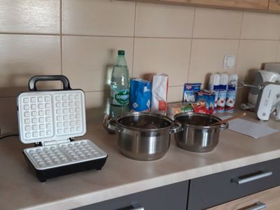 Gofrownice, garnki i składniki gotowe do przygotowania gofrów.