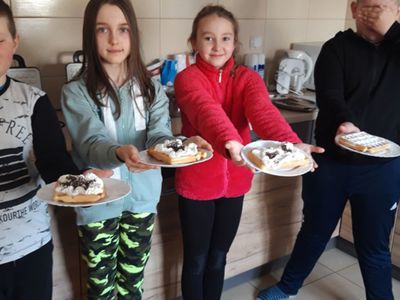 Wychowankowie z Placówki Wsparcia Dziennego z Kosierzewa prezentujący talerze z przygotowanymi goframi. 