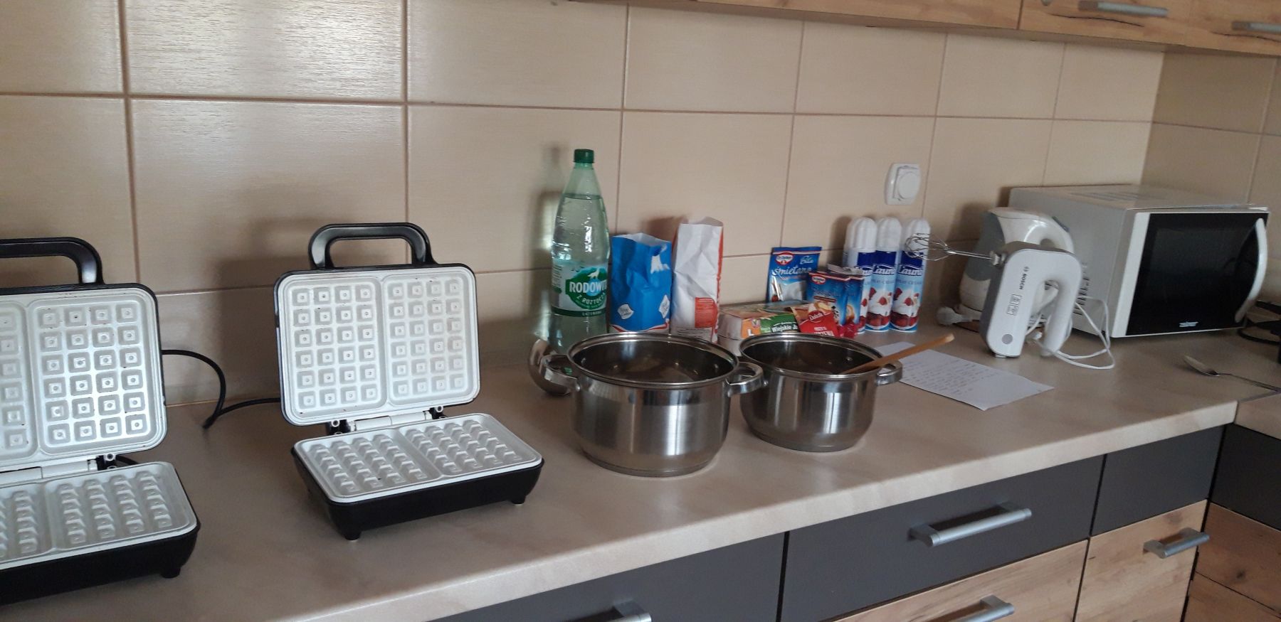 Gofrownice, garnki i składniki gotowe do przygotowania gofrów.