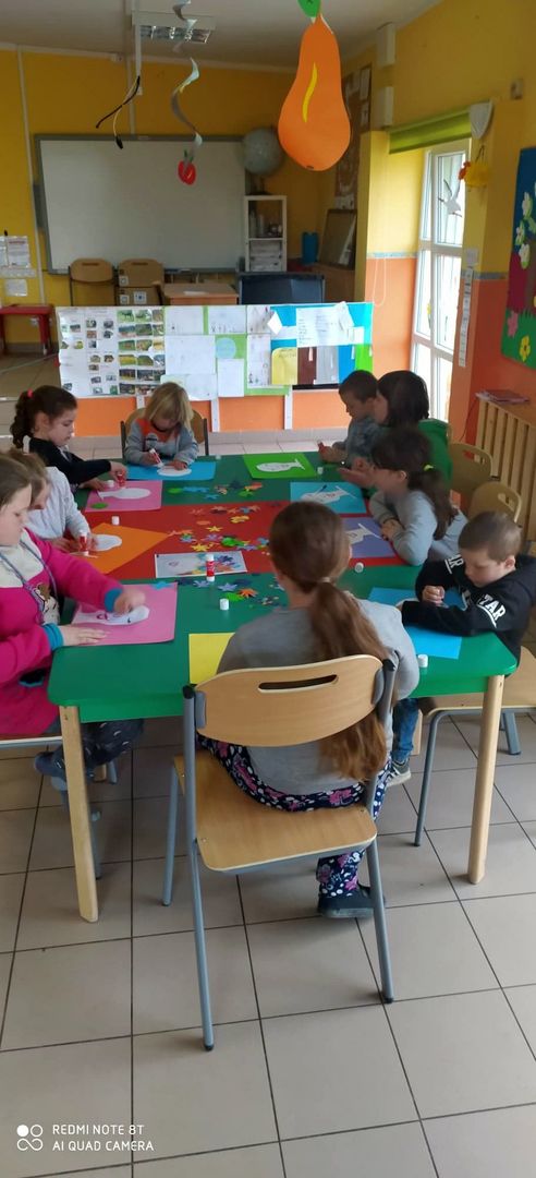 Dzieci wykonujące prace plastyczne z papieru.