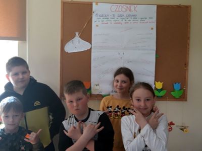 Grupa dzieci podczas zajęć w placówce wsparcia dziennego w Kosierzewie, w tle plakat nawiązujący do Dnia Czosnku.
