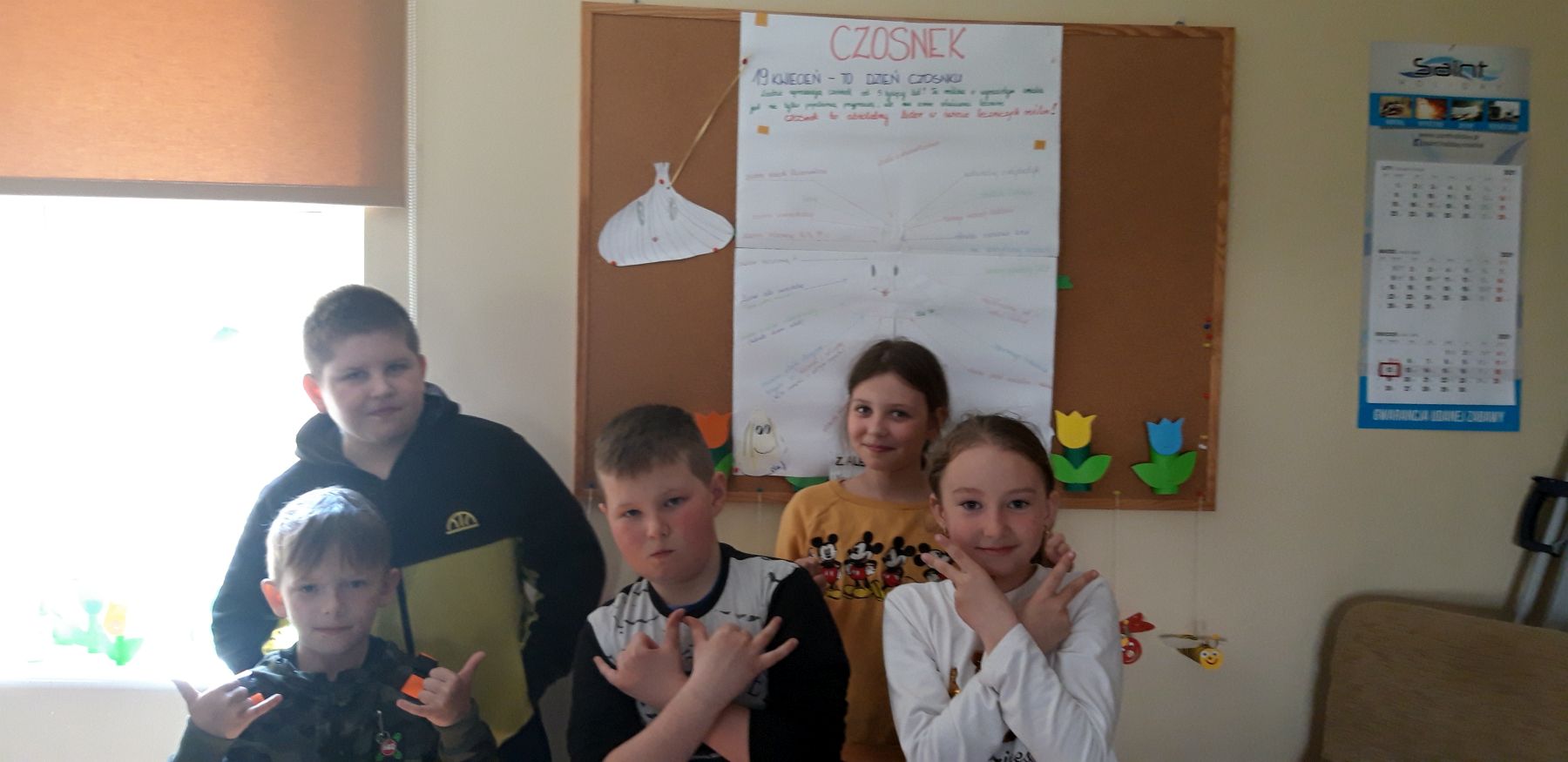 Grupa dzieci podczas zajęć w placówce wsparcia dziennego w Kosierzewie, w tle plakat nawiązujący do Dnia Czosnku. 