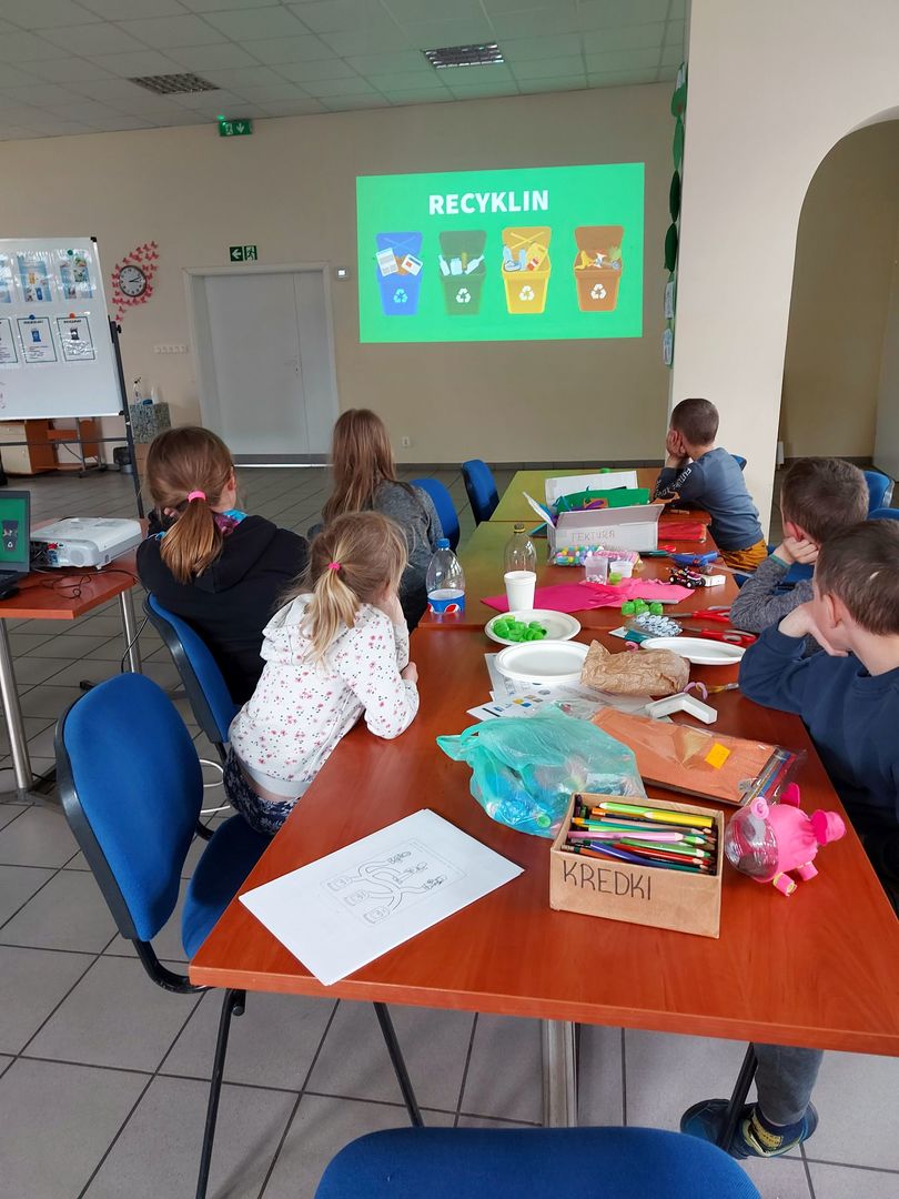 Podopieczni z Placówki Wsparcia Dziennego w Pękaninie w trakcie oglądania projekcji multimedialnej na temat recyklingu i ochronie Ziemi.