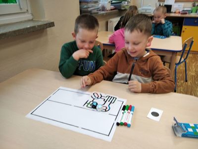 Chłopcy z Zespołu Szkół im. Mikołaja Kopernika w Ostrowcu obserwują ozoboty, które poruszają się po kolorowych torach.