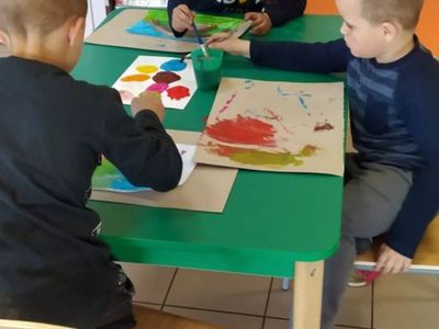 Wychowankowie Placówki Wsparcia Dziennego w Laskach malujący farbami.