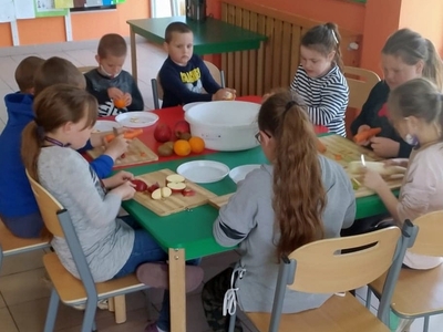 Zdjęcie przedstawia wychowanków obierających i krojących owoce i warzywa na sok.