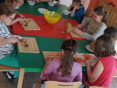 Zdjęcie przedstawia wychowanków krojących warzywa na sałatkę.