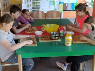Zdjęcie przedstawia wychowanków przygotowujących składniki do sałatki.
