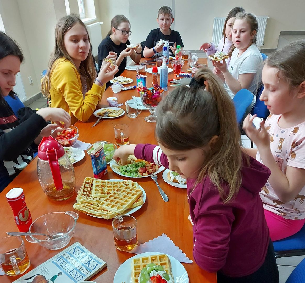 Podopieczni z  Placówki Wsparcia Dziennego w Pękaninie w trakcie degustacji przygotowanych przez siebie gofrów.
