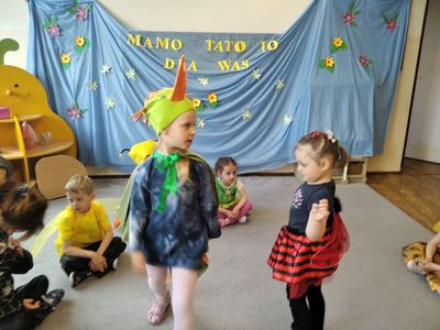 Dwie dziewczynki w strojach ptaszka i biedronki tańczą w środku koła utworzonego przez dzieci.